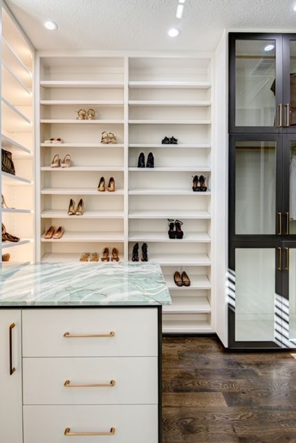 A walk in closet with lots of shelves and drawers filled with shoes.