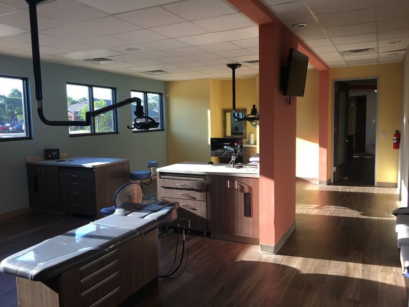 A modern office with a large desk , chairs , and a flat screen tv.