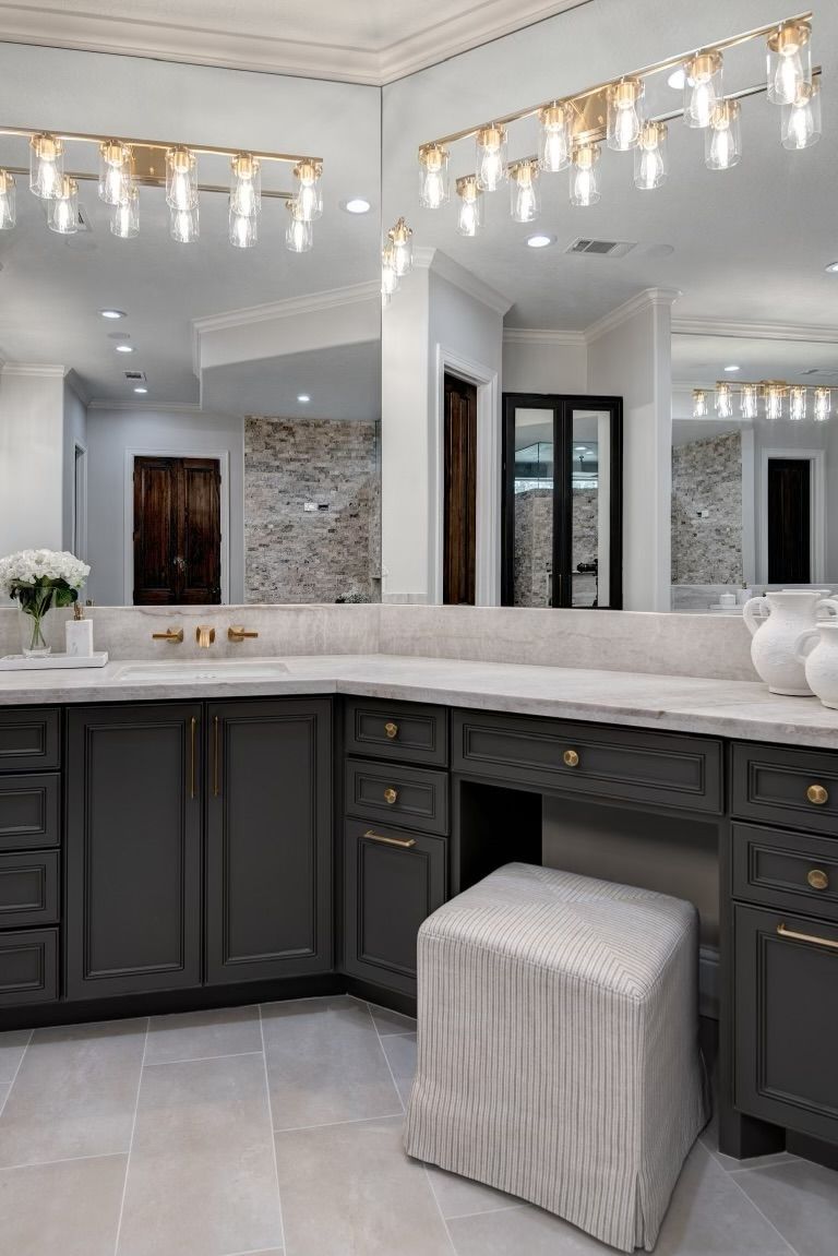 A bathroom with a vanity , sink , mirror and ottoman.