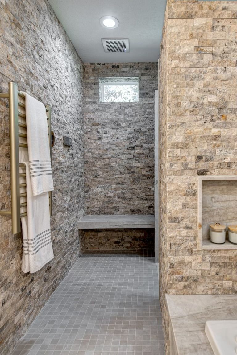 A bathroom with a walk in shower and a bench.