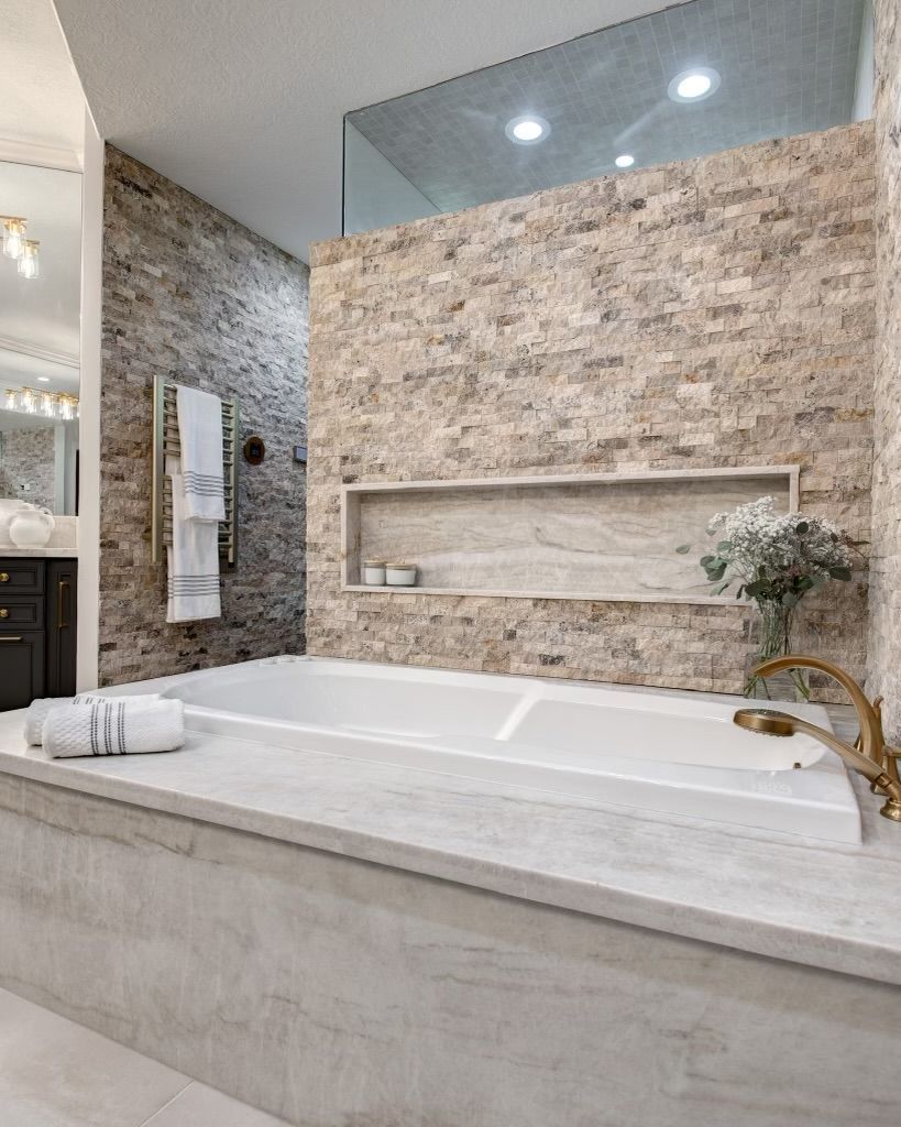 A bathroom with a large bathtub and a stone wall.