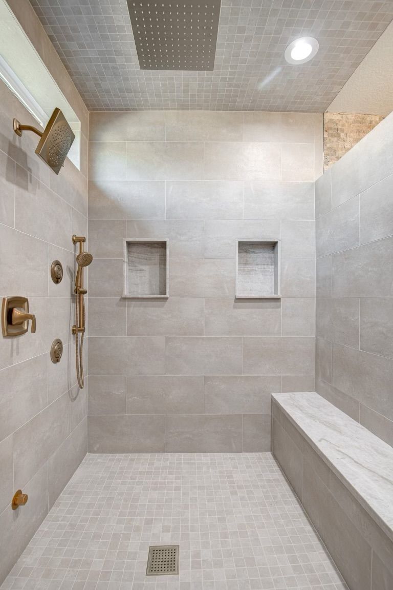 A walk in shower with a bench and a shower head.