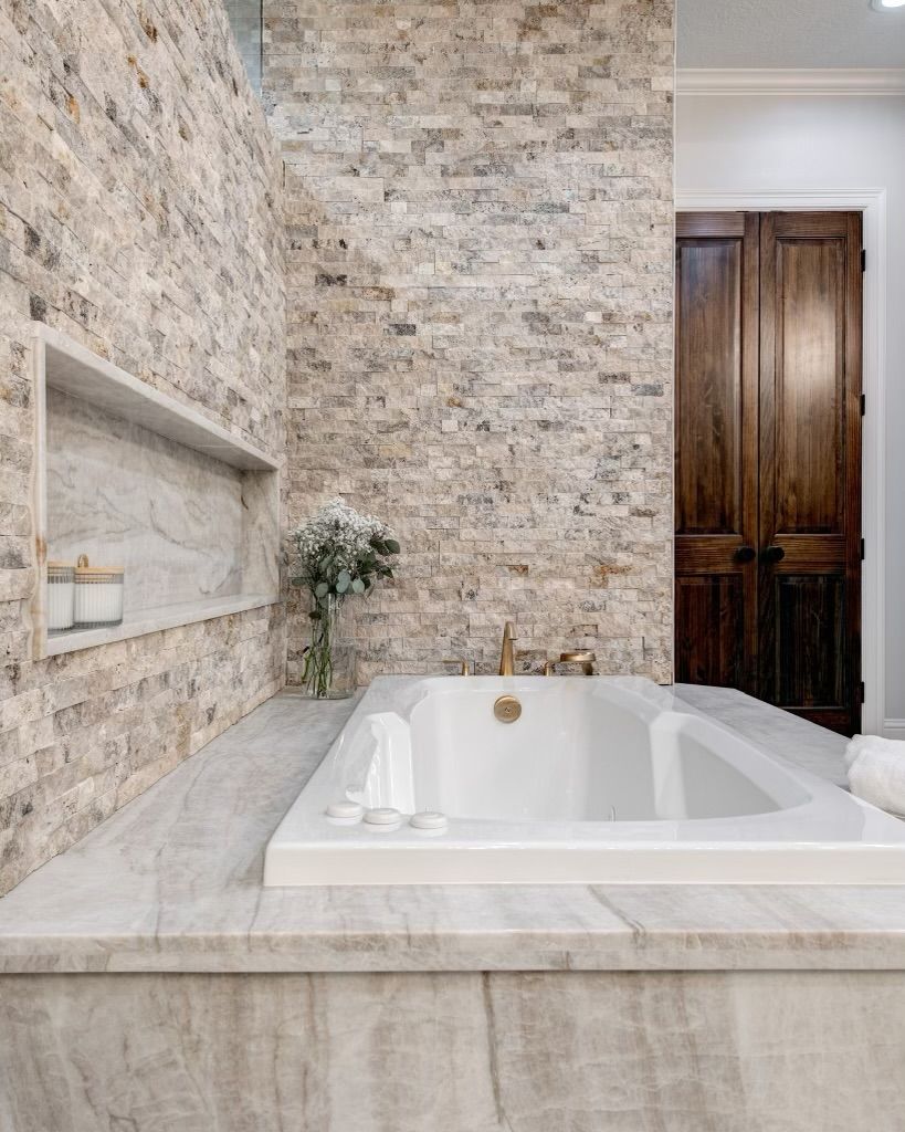 A bathroom with a bathtub and a brick wall.