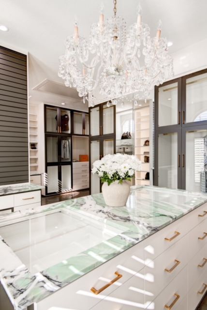 A large walk in closet with lots of drawers and a chandelier.