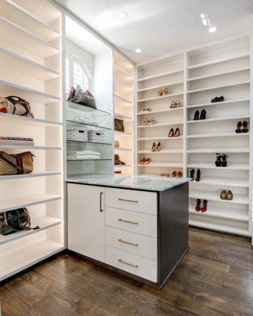 A walk in closet with lots of shelves and drawers