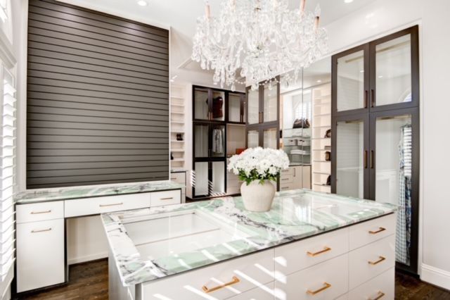 A walk in closet with a large island in the middle and a chandelier hanging from the ceiling.