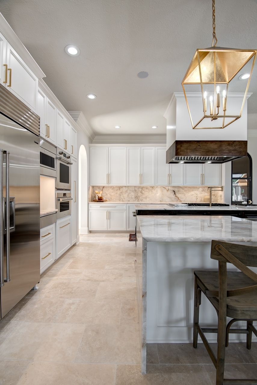 A kitchen with white cabinets , stainless steel appliances , and a large island.
