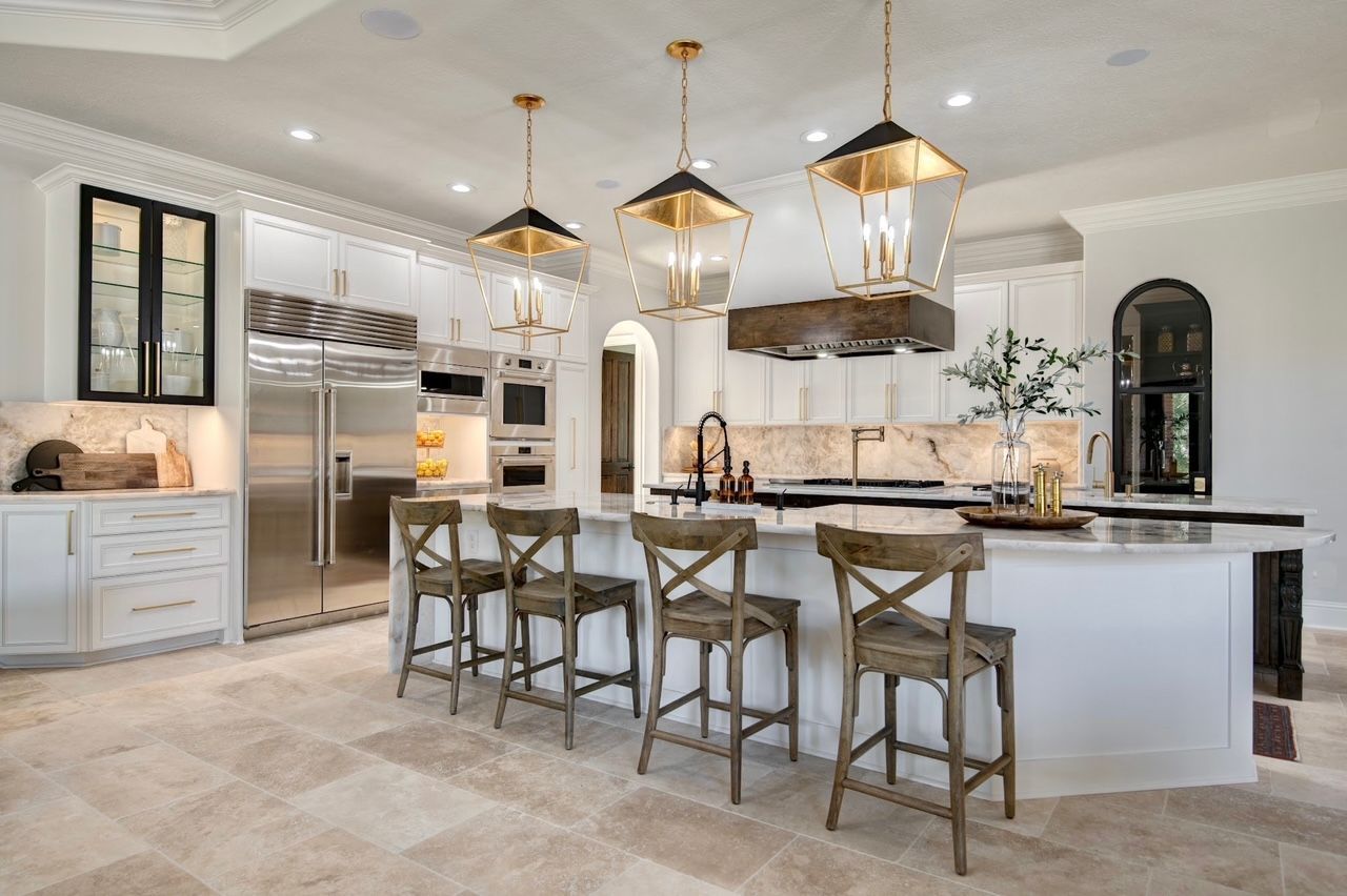 A kitchen with white cabinets , stainless steel appliances , a large island and stools.