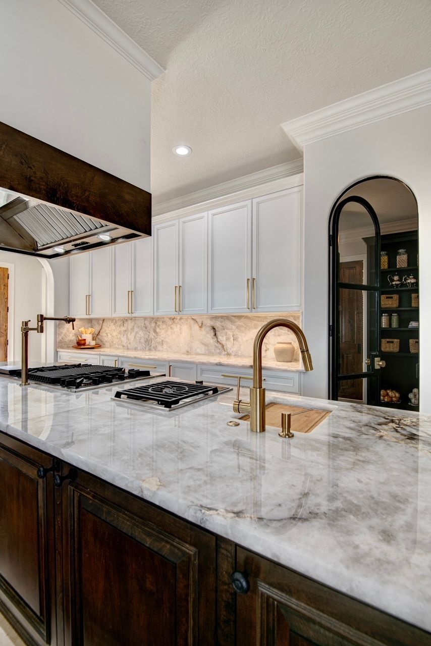 A kitchen with white cabinets and marble counter tops.
