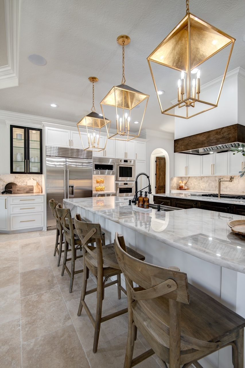 A kitchen with white cabinets , stainless steel appliances , a large island , and wooden stools.