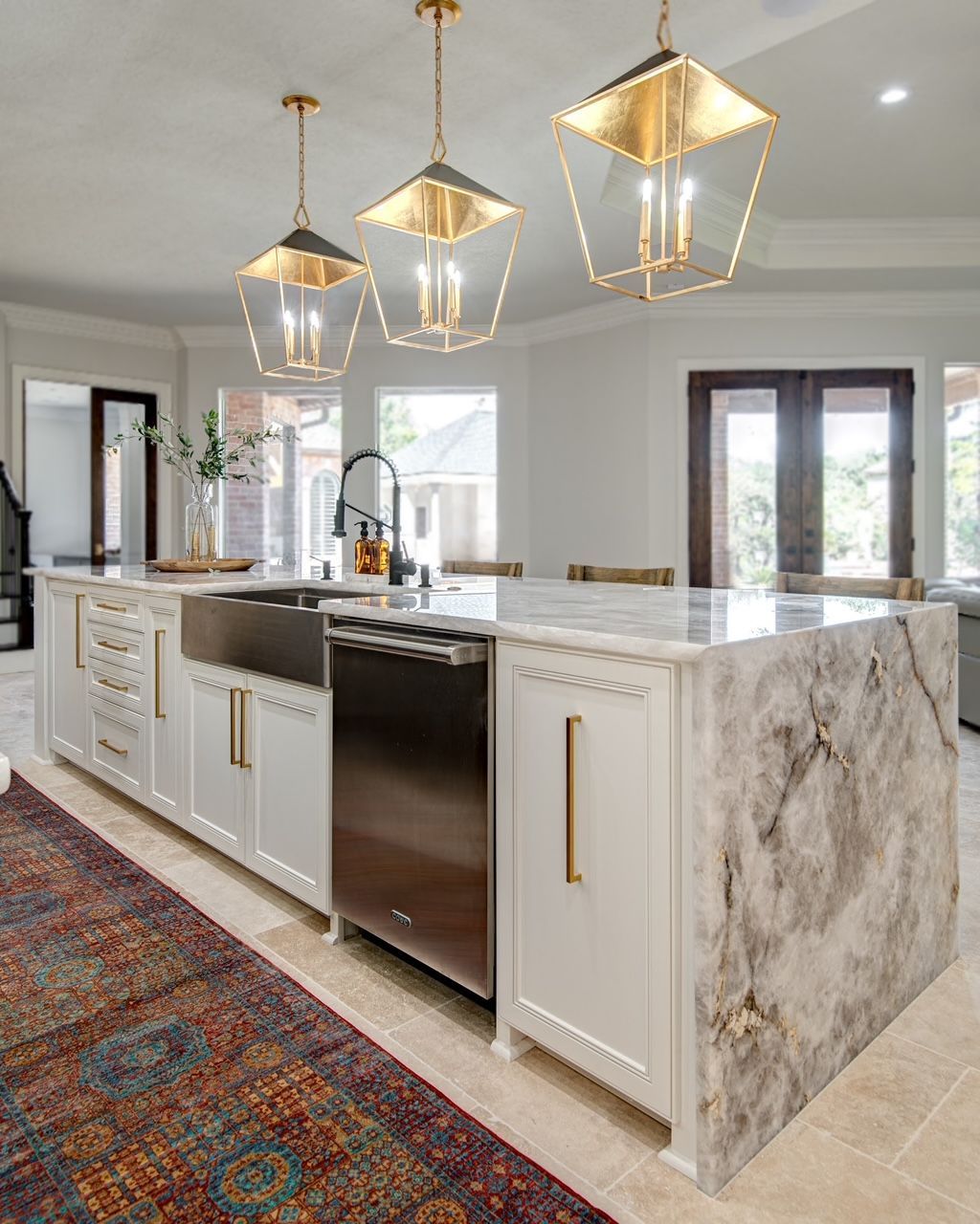 A kitchen with a large island , sink , dishwasher , and stainless steel appliances.