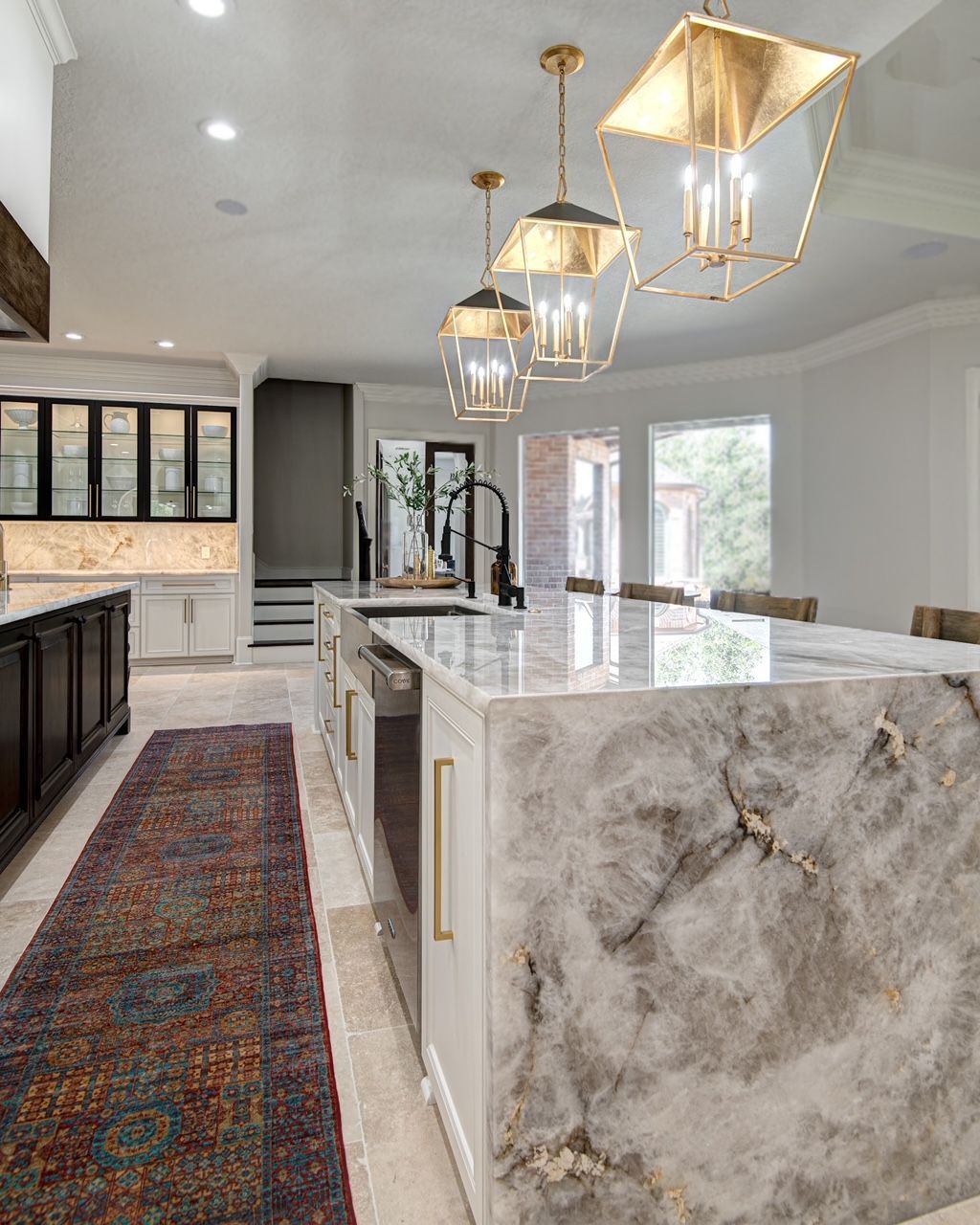 A kitchen with a large island in the middle and a rug on the floor.