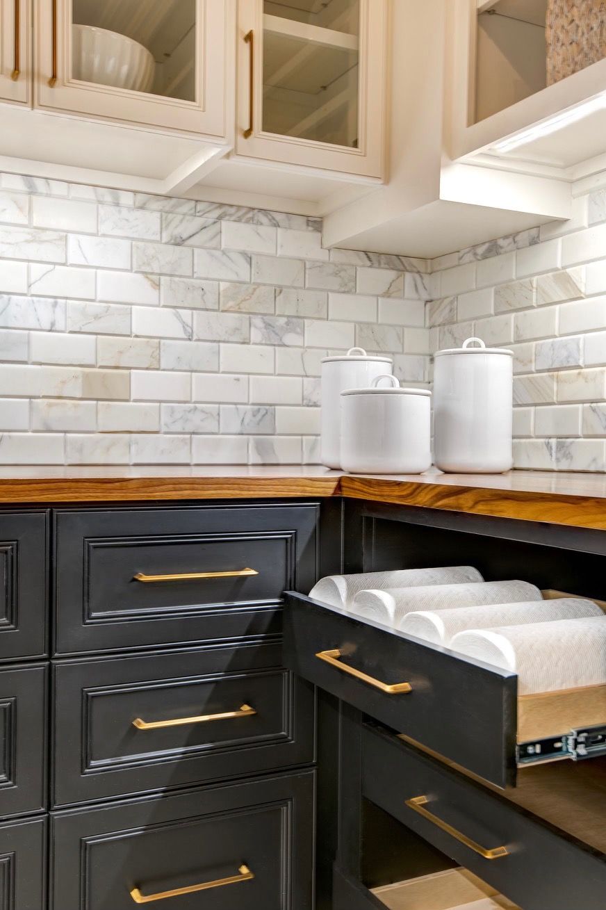 A kitchen with black cabinets and a drawer open.