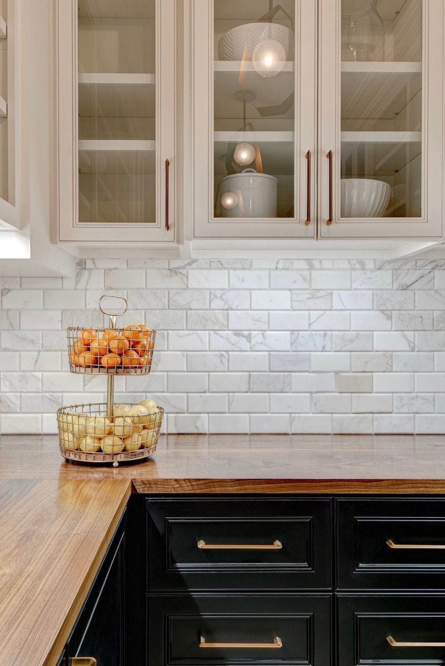 A kitchen with black cabinets , a wooden counter top , and a glass door.