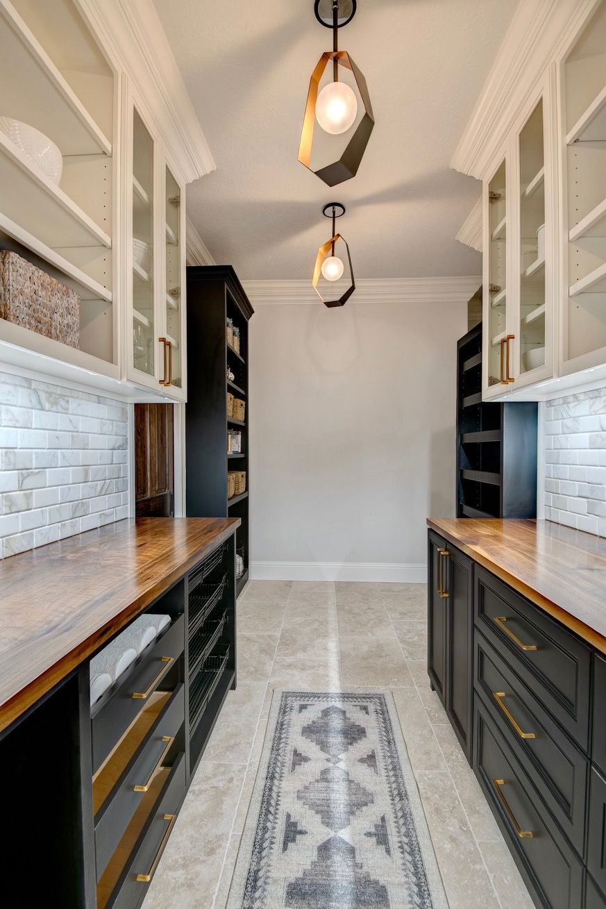 A pantry with lots of cabinets and drawers and a rug on the floor.