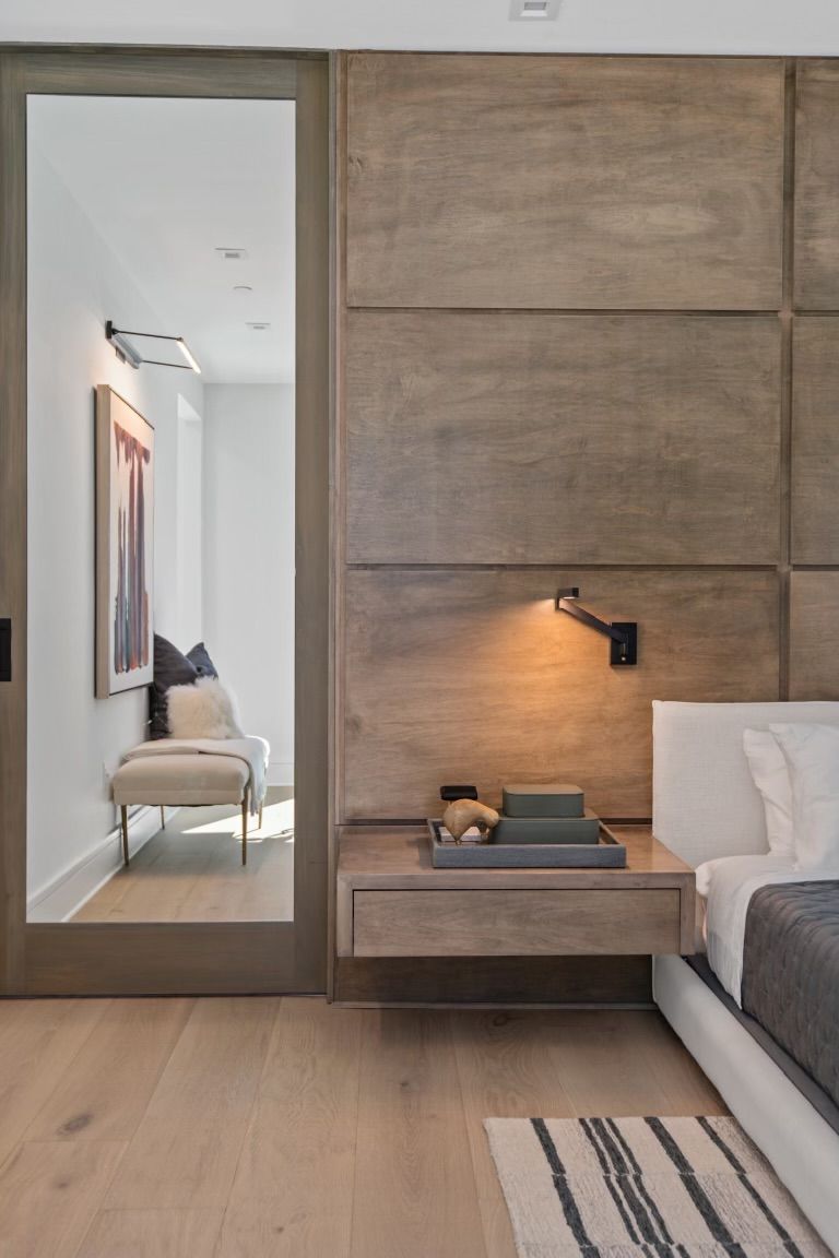 A bedroom with a bed , nightstand , and sliding glass door leading to a living room.
