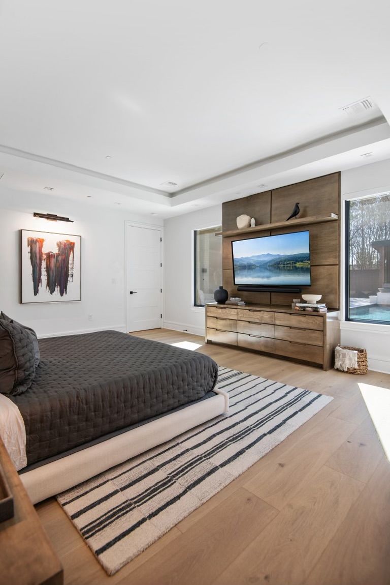 A bedroom with a bed , dresser , television and rug.