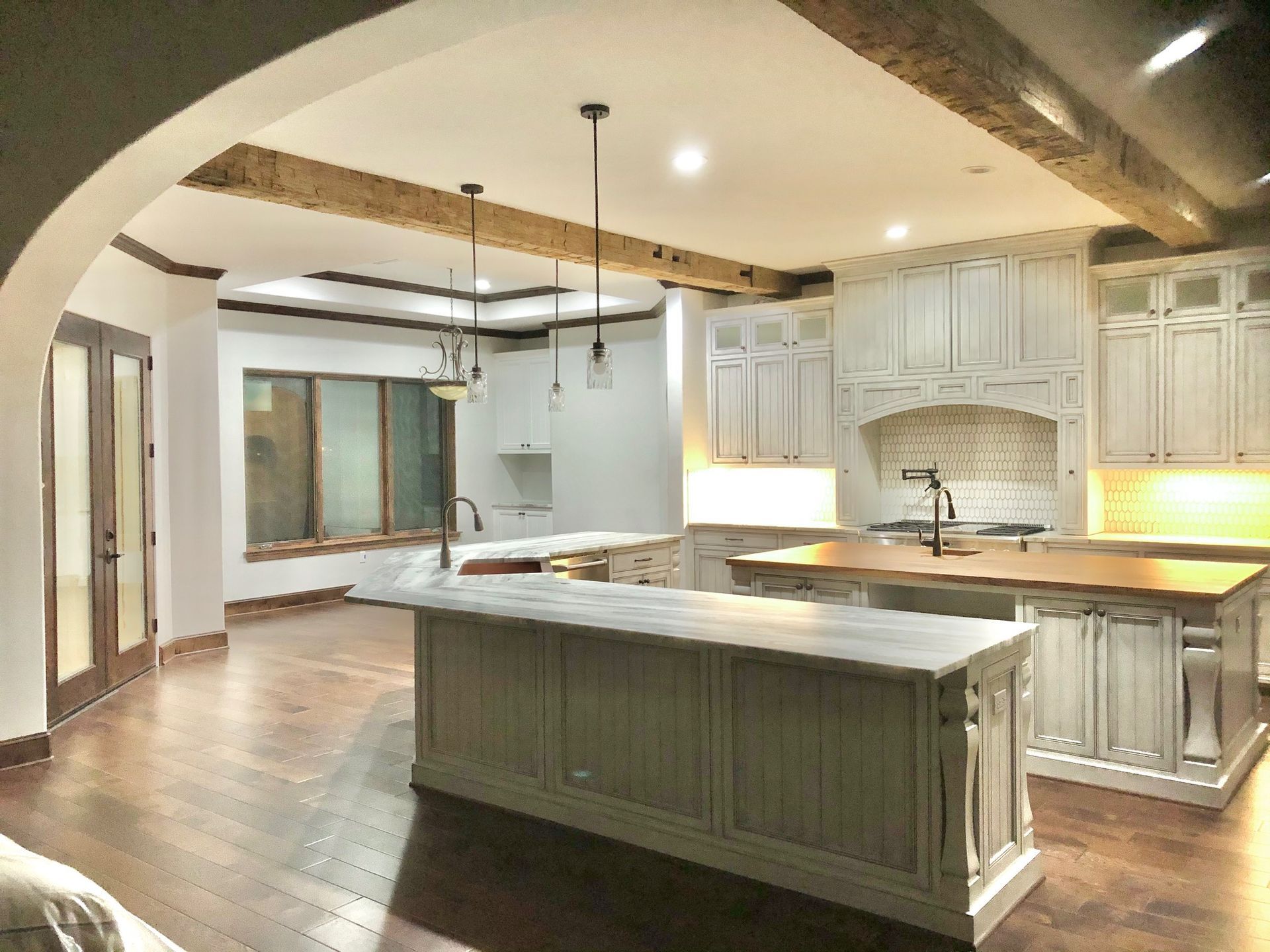 A kitchen and dining room in a house with white cabinets and hardwood floors
