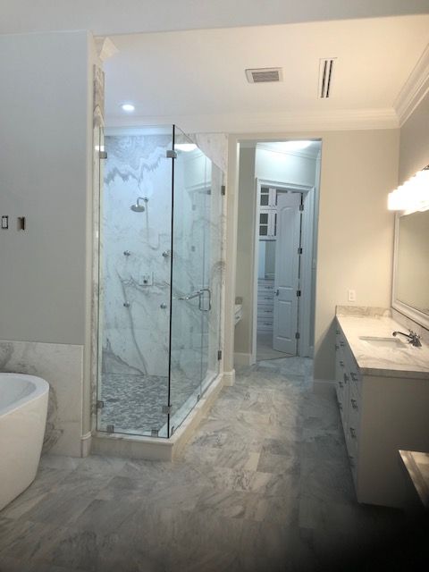 A bathroom with a walk in shower , toilet , sink and mirror.