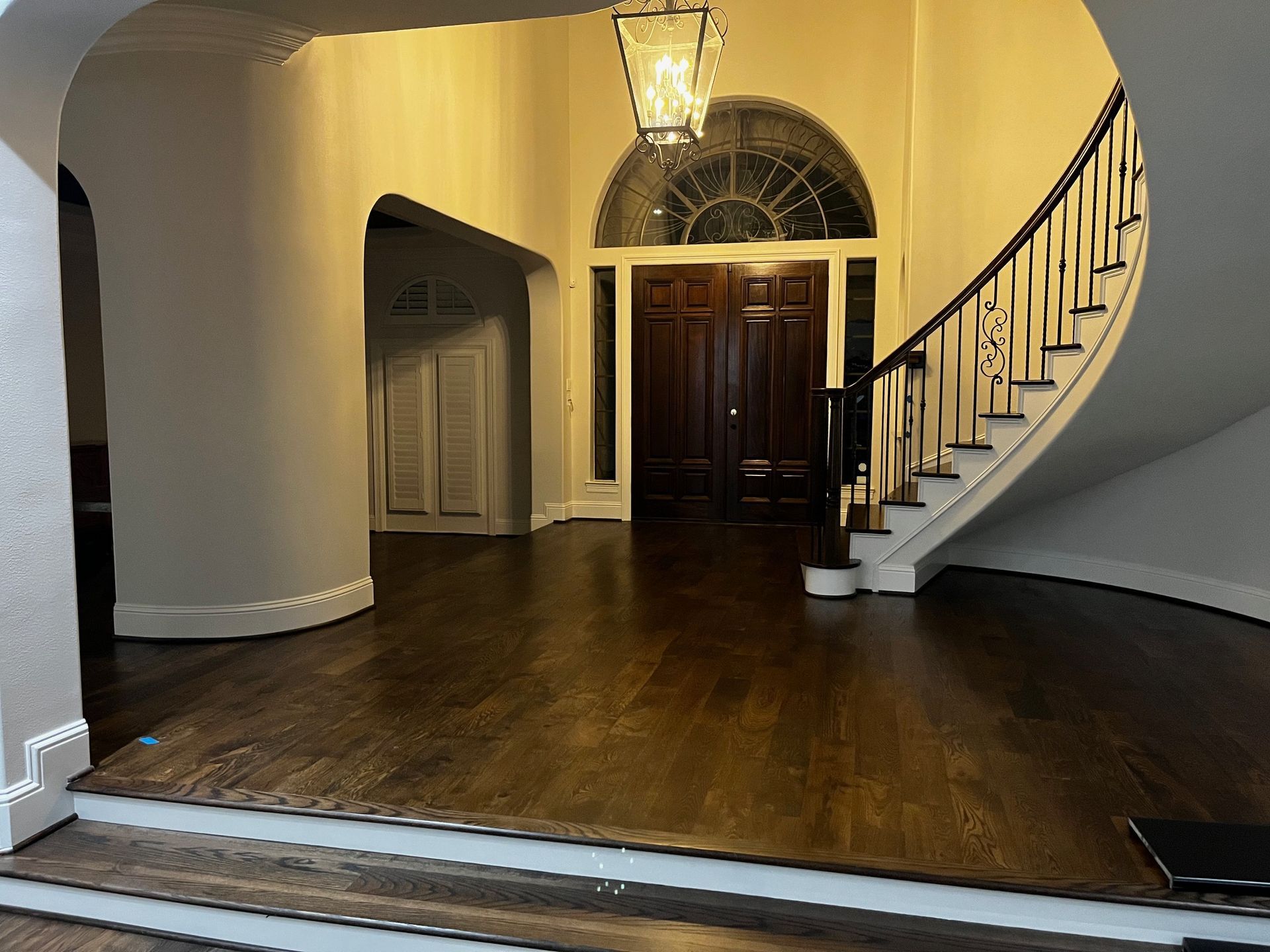 A large hallway with a curved staircase and a lantern hanging from the ceiling.