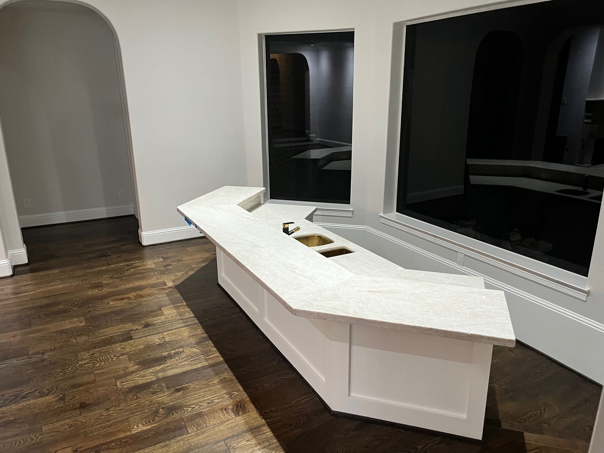 A long white counter in a room with wooden floors.