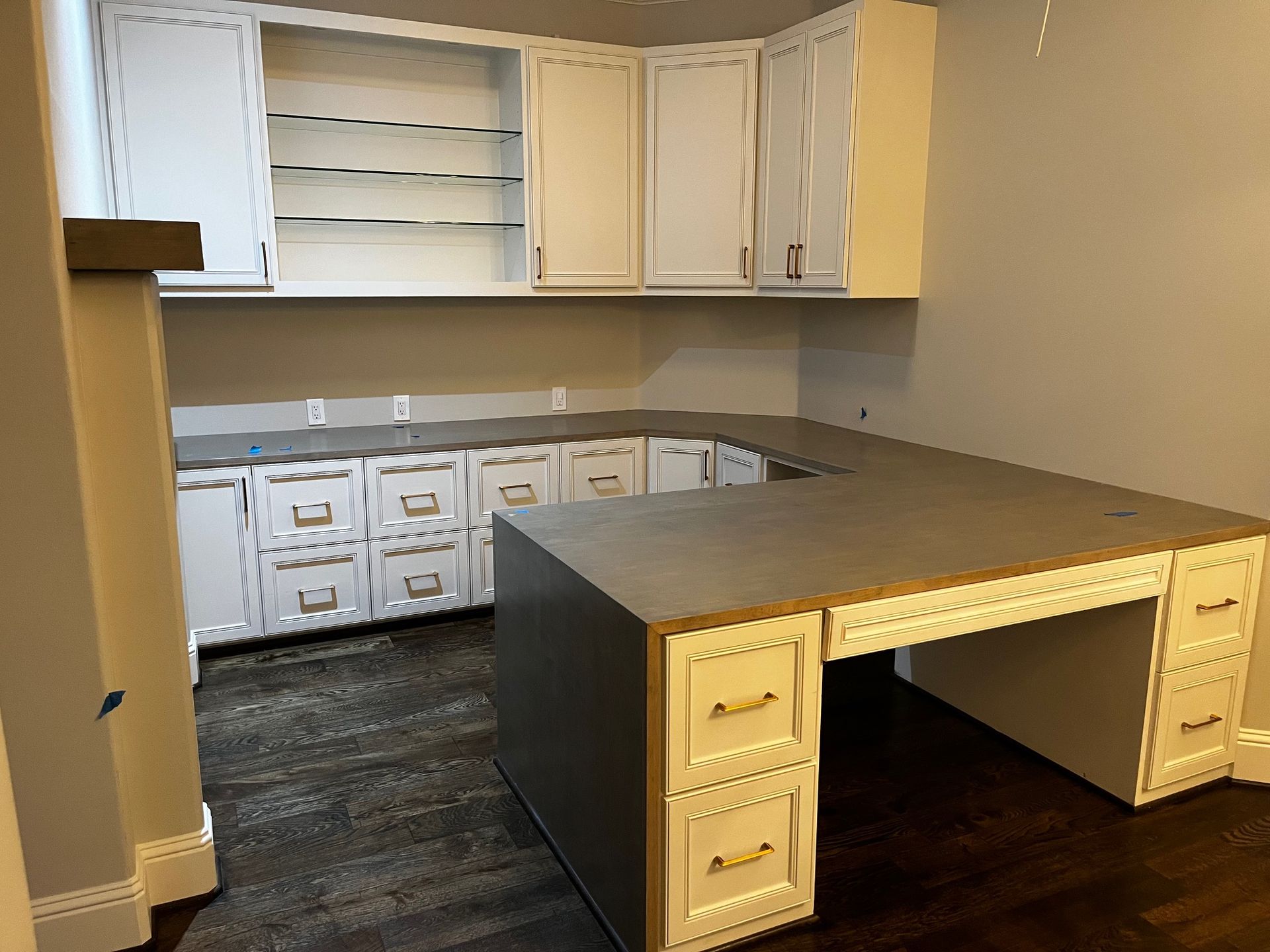 A kitchen with white cabinets and a large desk