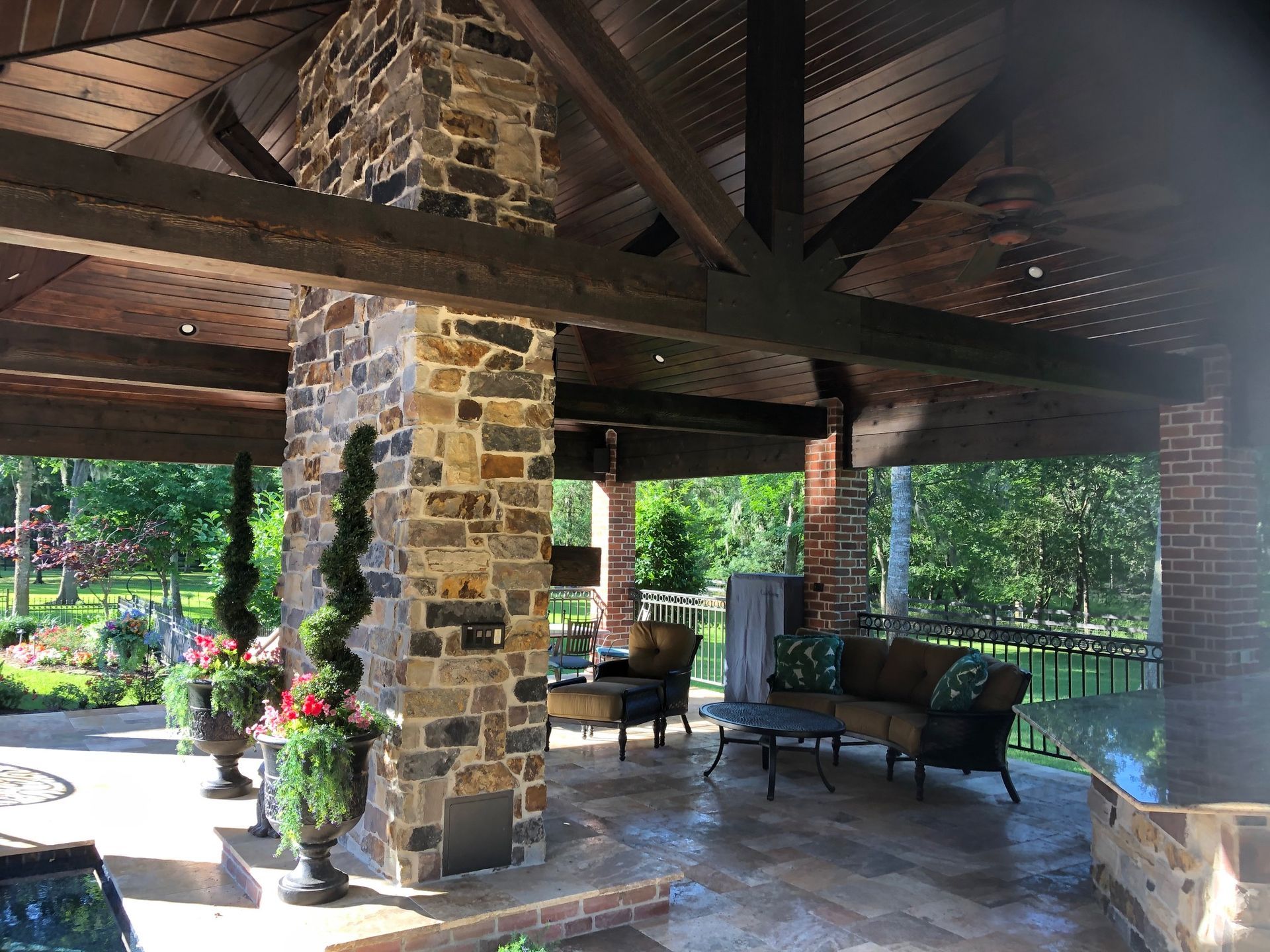 A patio with a couch , chairs , a table and a fireplace.