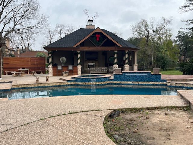 There is a large swimming pool in the backyard of a house.
