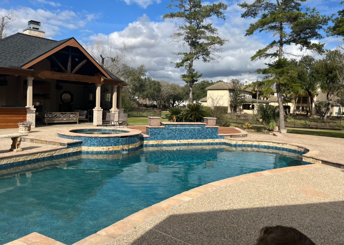There is a large swimming pool in the backyard of a house.
