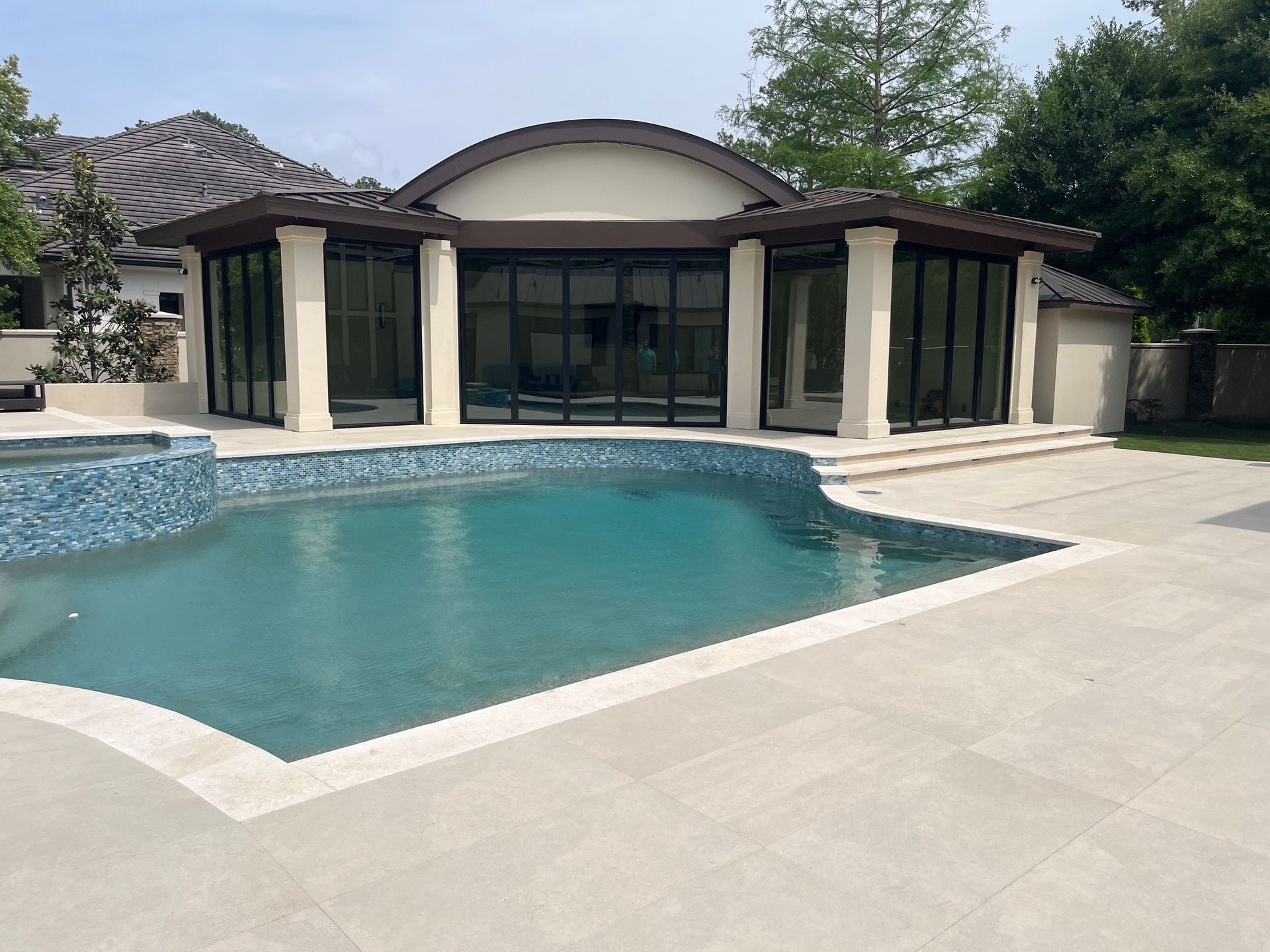 There is a large swimming pool in the backyard of a house.