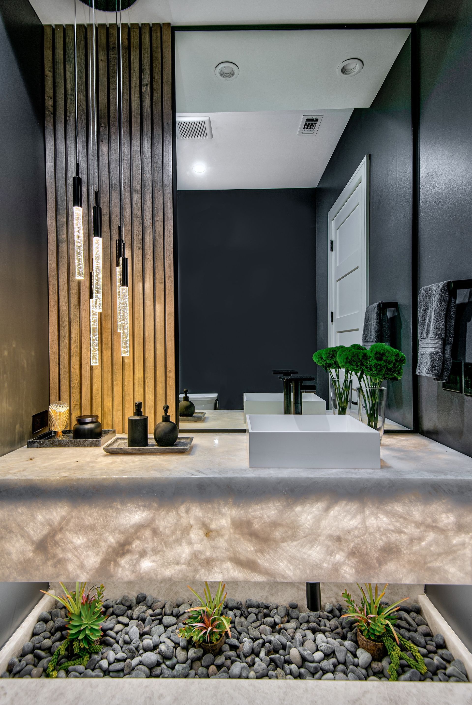 A bathroom with a sink , mirror , and plants.