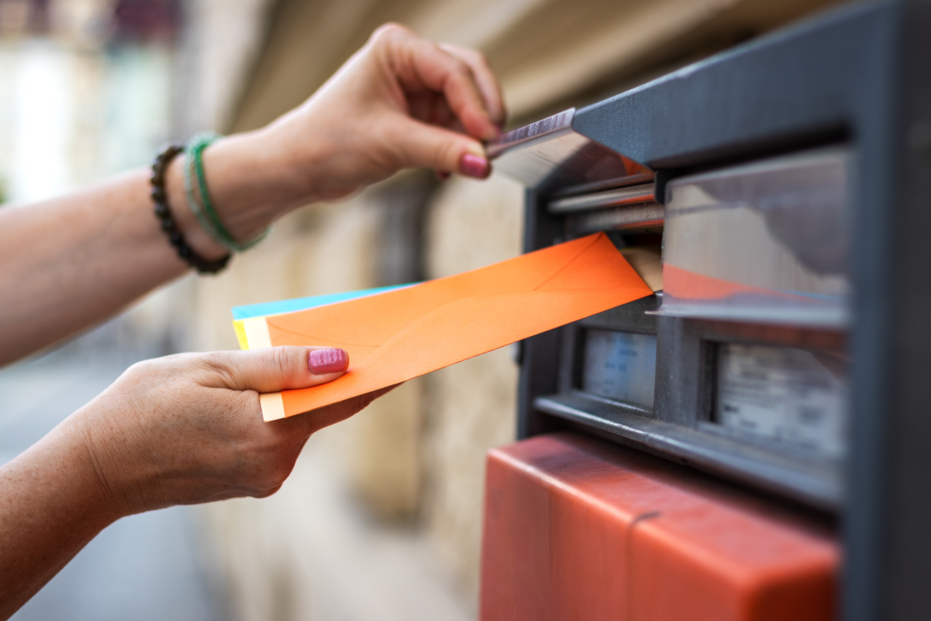 A woman is putting a letter in a mailbox.