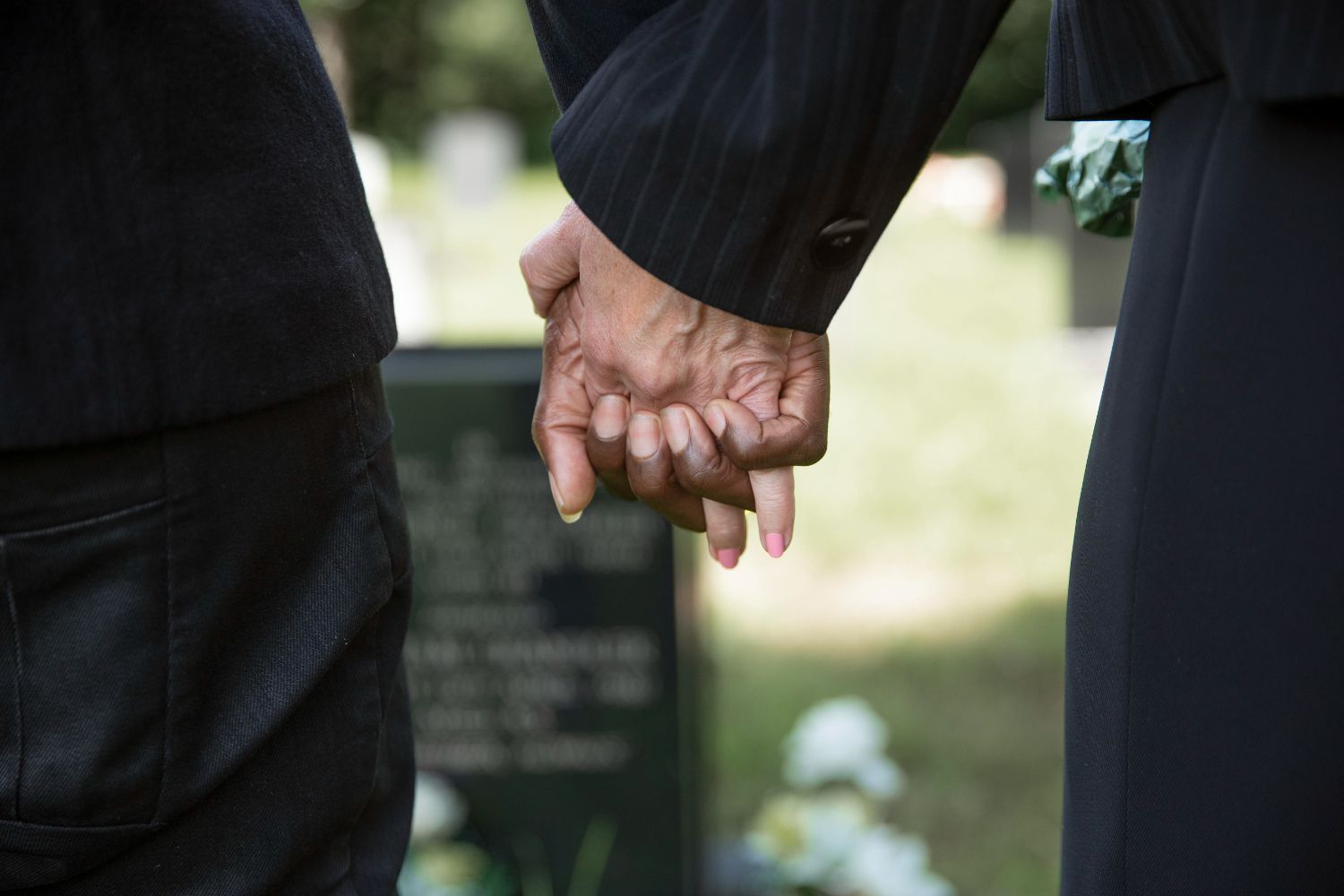 A man and a woman are holding hands in front of a grave.