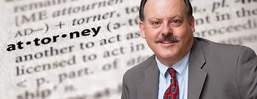 A man in a suit and tie is standing in front of a dictionary page.