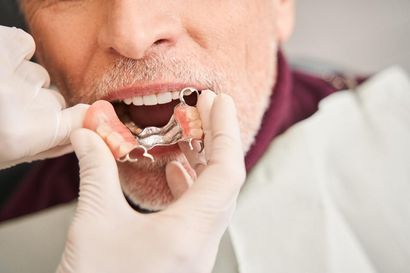 A Man is Getting a Denture From a Dentist — Burleigh Heads Denture Clinic Gold Coast in Burleigh Heads, QLD