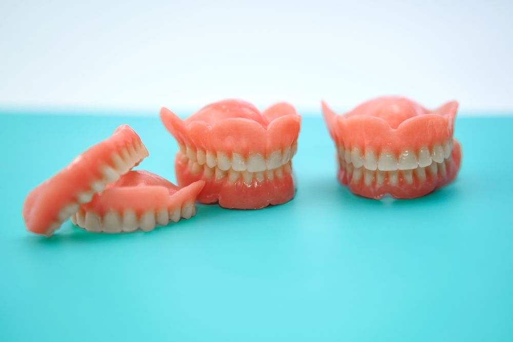 Three dentures are sitting on a blue table. — Burleigh Heads Denture Clinic Gold Coast in Burleigh Heads, QLD