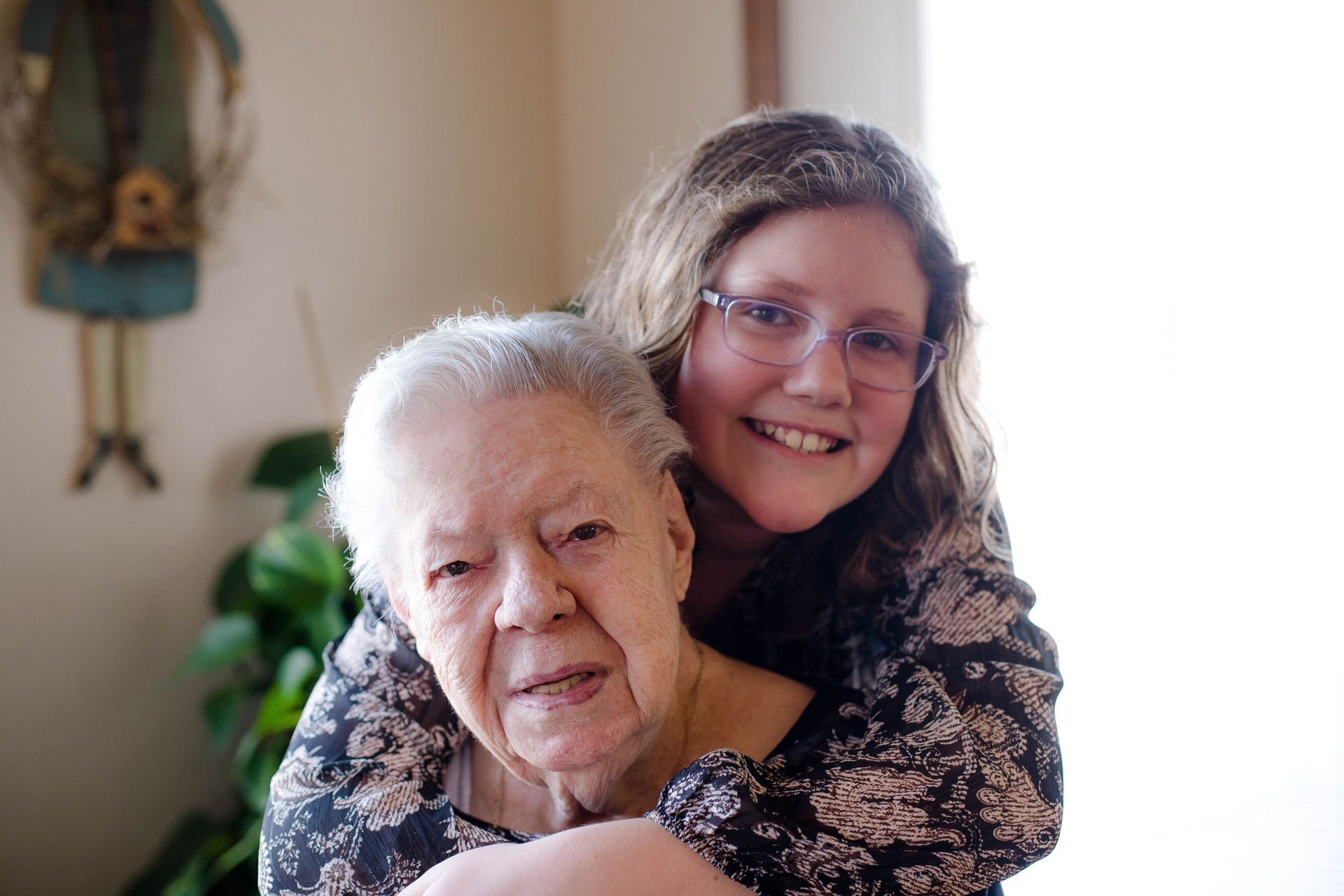A young girl is hugging an older woman in a living room.
