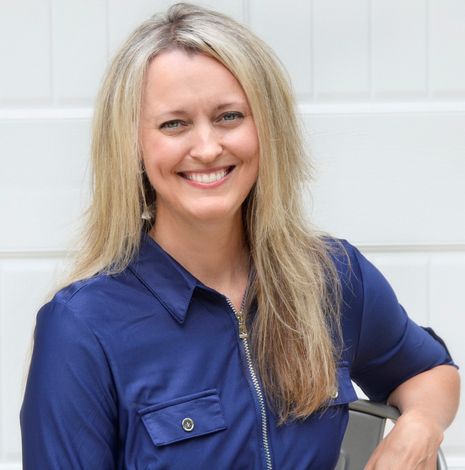 A woman in a blue shirt is smiling for the camera