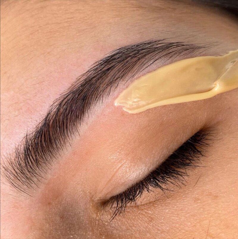 A close up of a woman 's eyebrow being waxed.