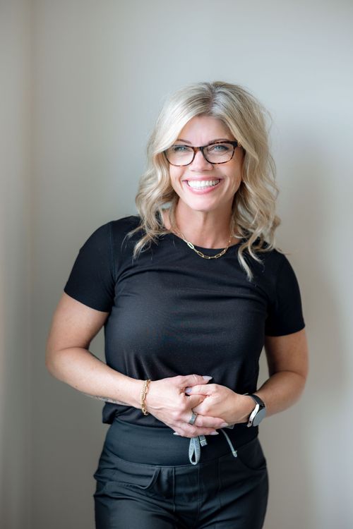 A woman wearing glasses and a black shirt is smiling for the camera.