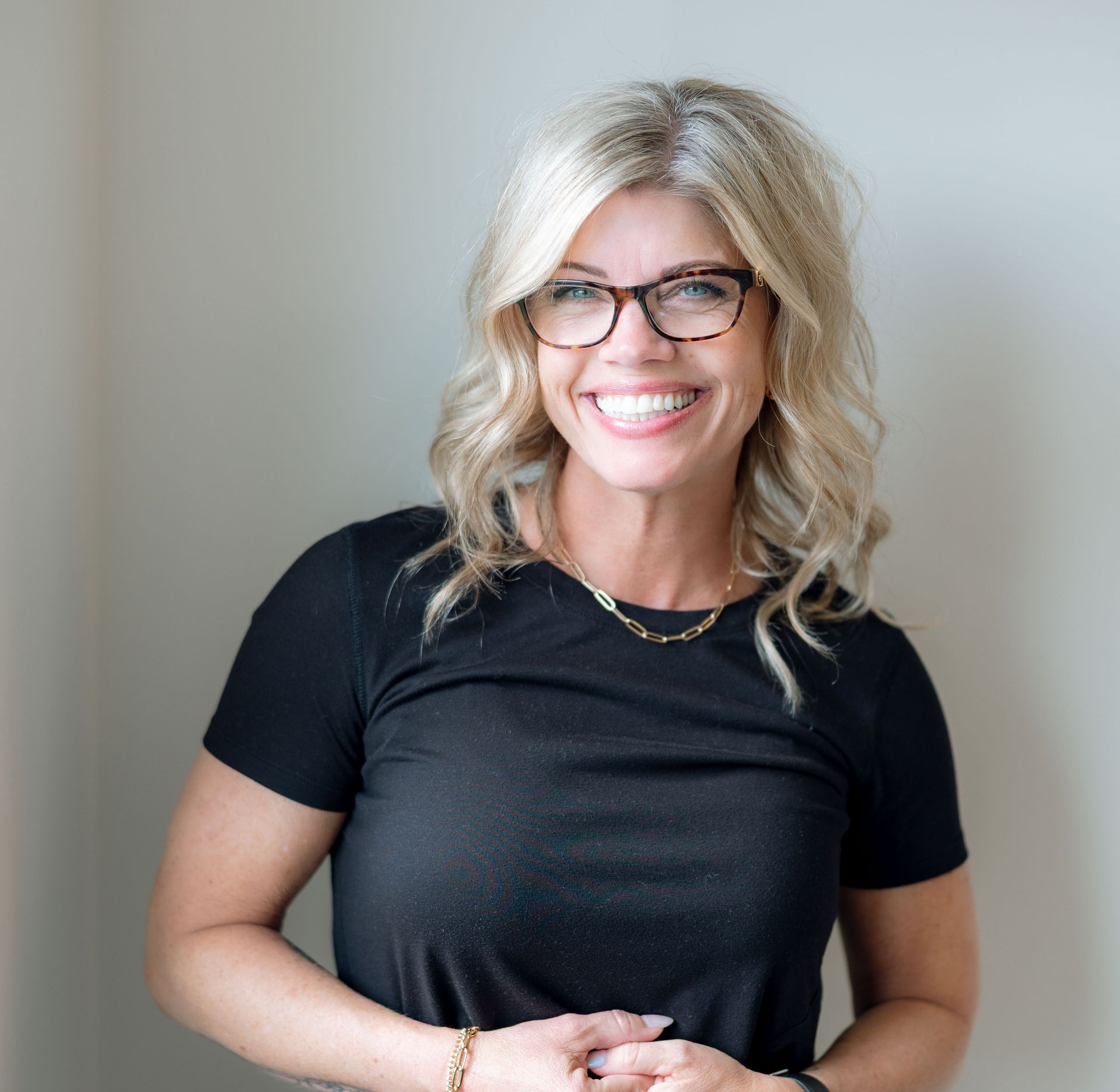 A woman wearing glasses and a black shirt is smiling for the camera.