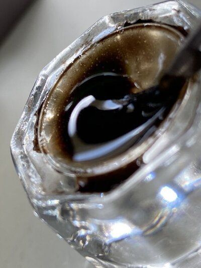 A close up of a bottle of liquid in a glass container.