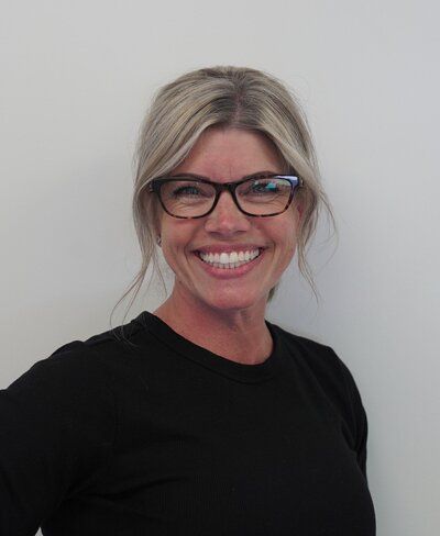 A woman wearing glasses and a black shirt is smiling for the camera.