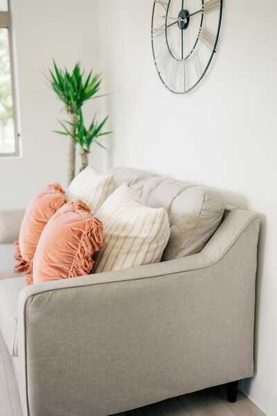 A living room with a couch and a clock on the wall.