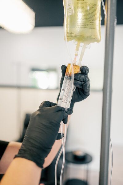 A person is holding a syringe and a bag of liquid.