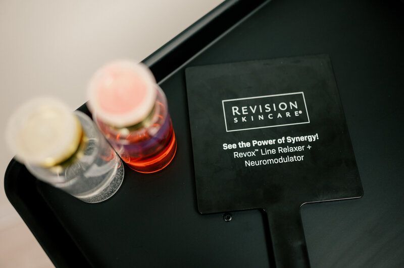 Two bottles of revision skincare are sitting on a black tray.