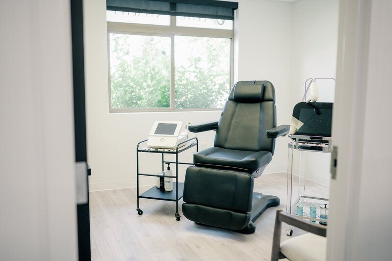 A doctor 's office with a chair and a window.