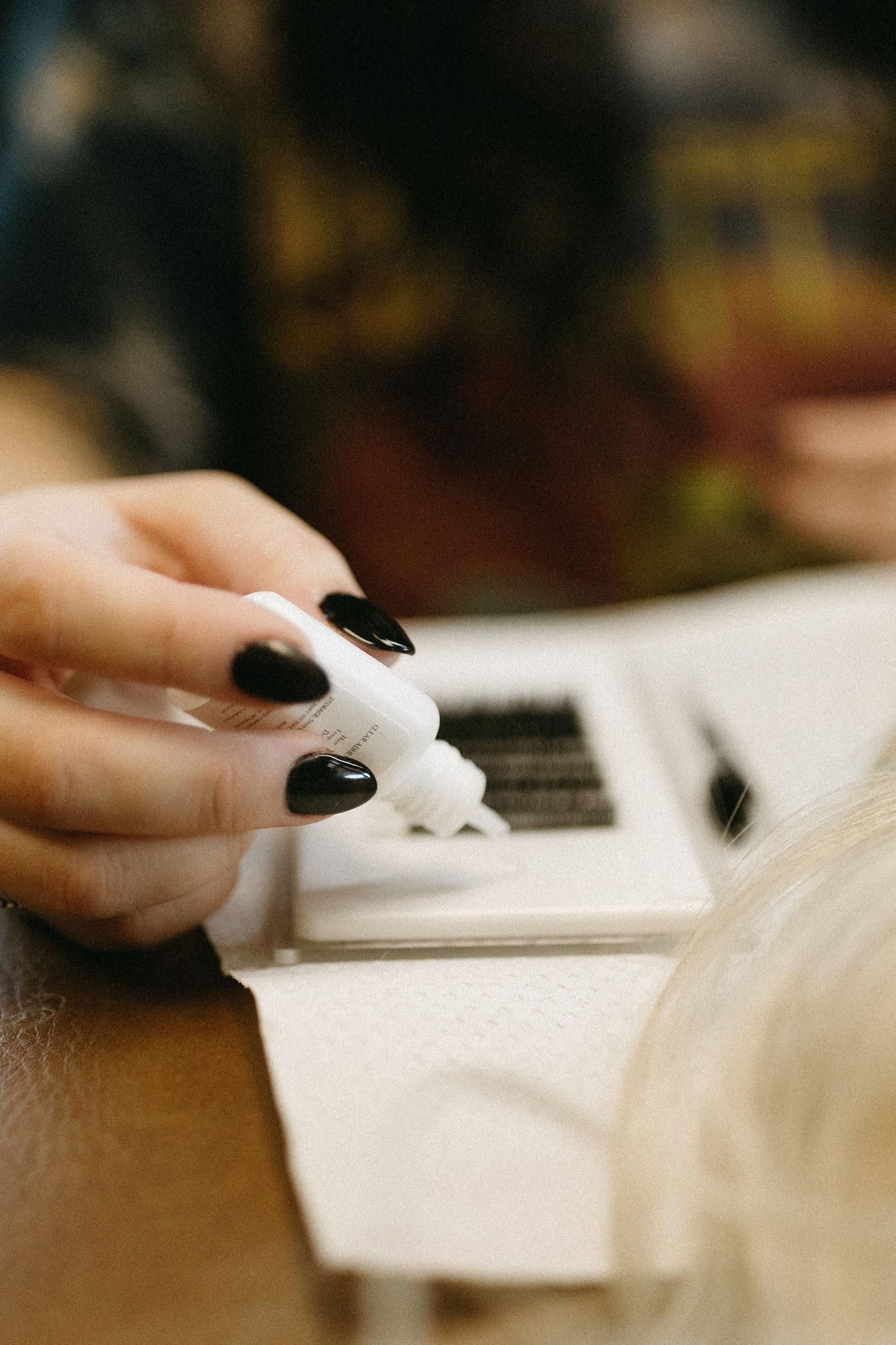 A woman is applying eyelash extensions to a woman 's eye.