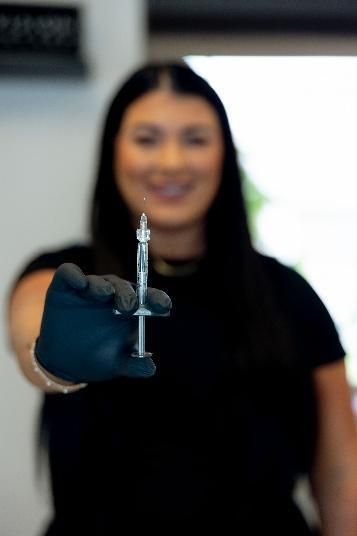 A woman is sitting in a chair while a doctor examines her face.