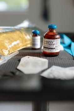 A person is holding a syringe and a bag of liquid.
